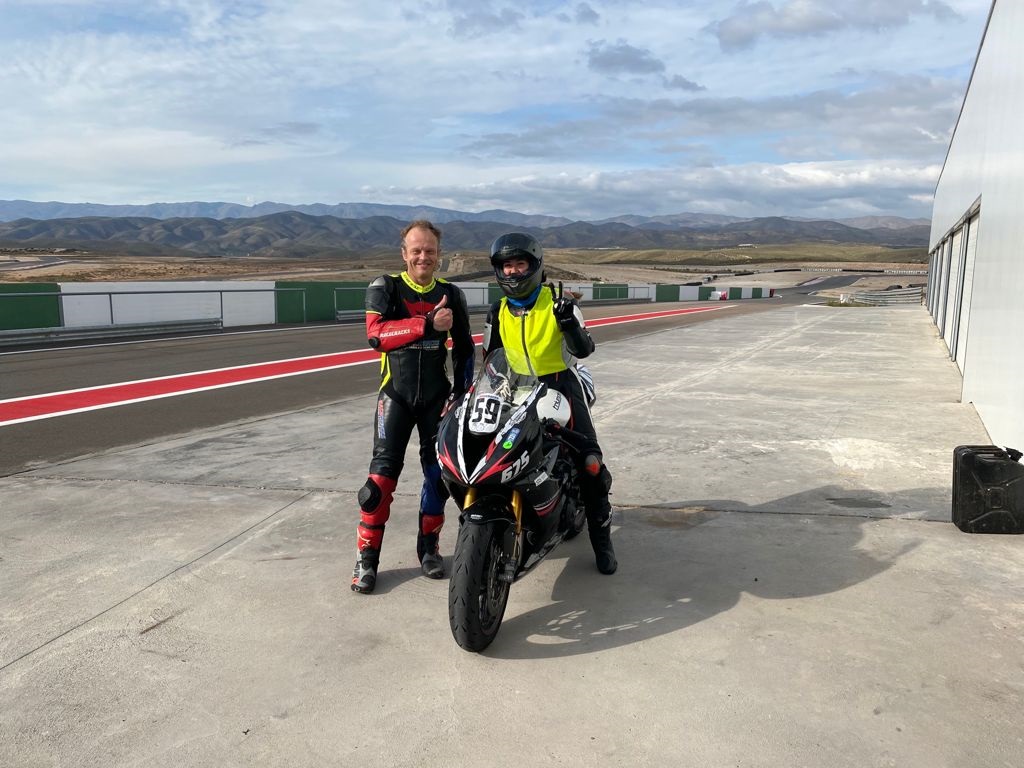 Coach en rijder met de motor op het circuit, klaar voor een trackday